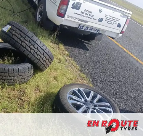 EN ROUTE TYRES technician performing a roadside tyre repair on a car with a damaged tyre.